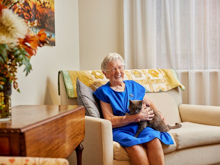 Resident patting cat on the couch