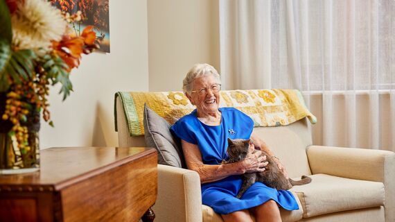 Resident patting cat on the couch