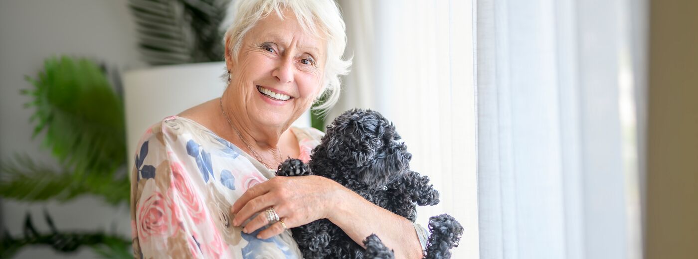 A cute senior woman with poodle on the living room